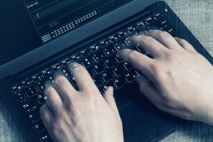 hacker's hands on laptop keyboard